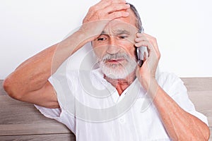 Elderly man with headache in bed calling the doctor