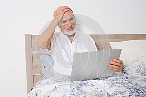 Elderly man with headache in bed looking for a doctor