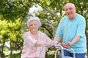 Elderly man helping his wife with walking frame