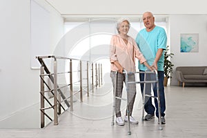 Elderly man helping his wife with walking frame