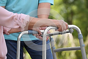 Elderly man helping his wife with walking frame