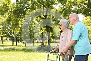 Elderly man helping his wife with walking frame