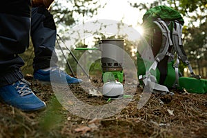 Elderly man hiker cooking food in forest, closeup view on portable gas burner