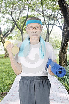 Elderly man holding a dumbbell in the park