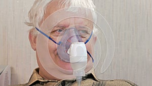 An elderly man holding a mask from an inhaler at home. Treats inflammation of the airways via nebulizer. Preventing