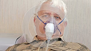 An elderly man holding a mask from an inhaler at home. Treats inflammation of the airways via nebulizer. Preventing