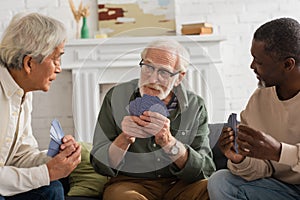 Elderly man holding playing cards near