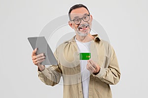 Elderly man holding a tablet and credit card