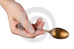 An elderly man holds in his hand a vintage spoon with a dull oxidized gold coating. Isolated