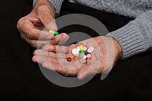 An elderly man holds a lot of colored pills in old hands. Painful old age. Health care of older people