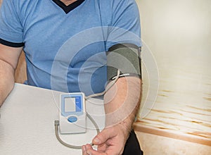 An elderly man independently measures his blood pressure and heart rate using a digital pressure gauge, prevention of hypertension