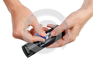 An elderly man installs a new, fresh battery in the remote control of a modern TV isolated