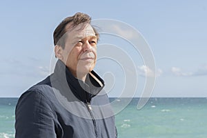 Elderly man in jacket against sea and sky.