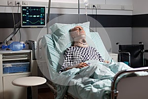 Elderly man laying in hospital room bed wearing cerival collar
