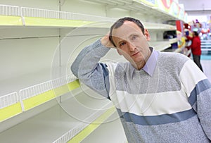 Elderly man leans against empty shelves