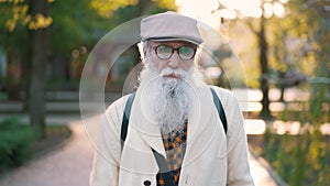 Elderly man with long white beard and glasses walks down the street