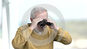 Elderly man looking through binoculars.