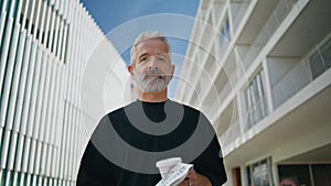 Elderly man looking camera on street closeup. Smiling bearded senior drinking