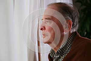 Elderly man looking out window