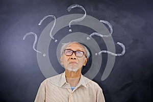 Elderly man looking at question marks