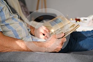 An elderly man looks through an album with old photographs, a concept of memories of youth, childhood, remembering his life,