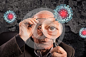 Elderly man looks with magnifier a covid19 coronavirus