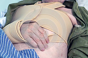 An elderly man is lying in the trauma department of the hospital with a broken collarbone in a bandage. High body photo