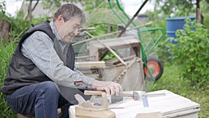 An elderly man makes a house for bees in the summer