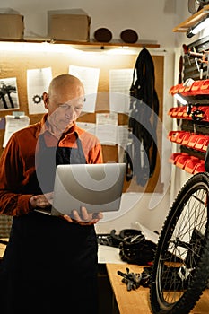 elderly man Mechanic checking data on a laptop in workshop or garage during servicing or bike repair.