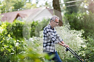Elderly man mowing the lawn