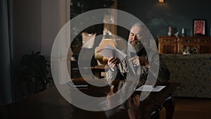 Elderly man opening envelope with knife in ancient cabinet. Old man