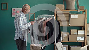 Elderly man owner startup business work with clothes at home prepare parcel delivery in sme supply chain