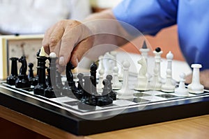 An elderly man plays chess. White pieces win