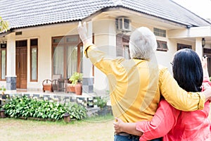 Elderly man pointing to his wife a comfortable residential house