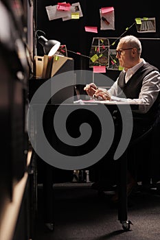 Elderly man police officer sitting at desk table