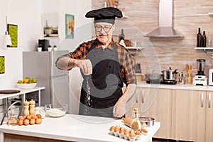 Elderly man preparing food spreading flour