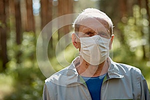 An elderly man in a protective mask walks in the Park, a walk in the fresh air after quarantine, a precautionary measure