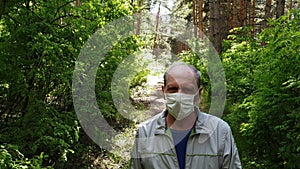 an elderly man in a protective mask walks in the Park, a walk in the fresh air after quarantine, a precautionary measure