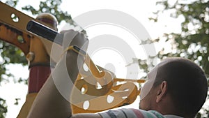 An elderly man pulls himself up on a horizontal bar on a street sports field.