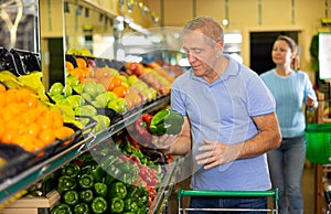 Elderly man purchaser buying pepper in grocery store