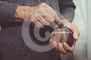 An elderly man puts a coin in an empty wallet. Poverty in retire