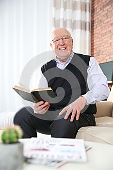 Elderly man reading book in living room