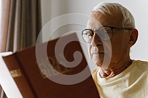 Elderly man reading holy bible at home