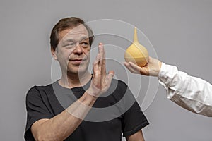 An elderly man refuses an enema offered to him by a doctor.