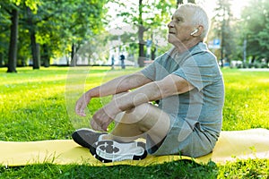 Elderly man relaxing in green city park after his workout