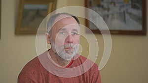 An elderly man rests looking at art objects while sitting on a bench in a Museum.