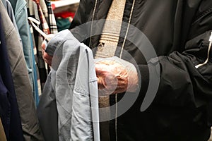 Elderly man's hands touching and feeling clothing fabric in store