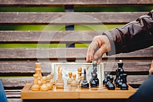 Elderly man senior holds chess piece game board outdoors