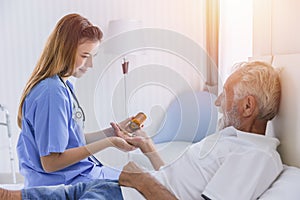 Elderly man senior people lay on bed health care giving medicine pills from nurse at homecare