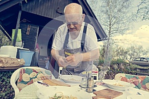 Elderly man setting a table outside.